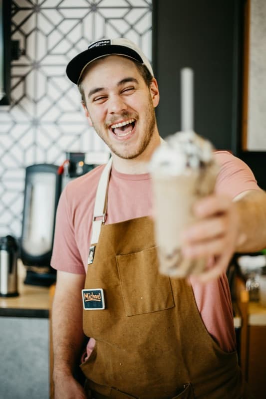 A smiling barista serving a drink